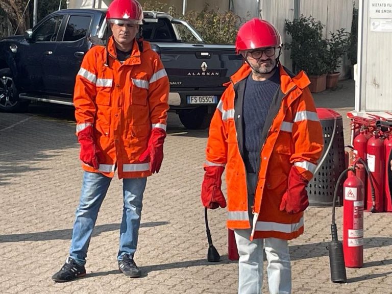 Due partecipanti a un corso antincendio con giacca ignifuga, casco e guanti protettivi
